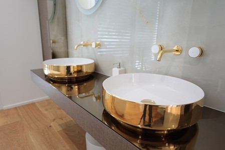 Badezimmer mit zwei goldfarbenen Aufsatzbecken und Wandarmaturen