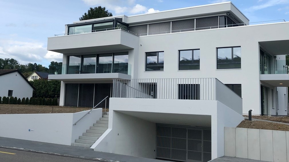Weisses Mehrfamilienhaus mit Terrassen an der Hauptstrasse in Hausen